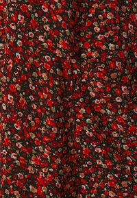 Tissu fleuri avec un fond noir orné de petites fleurs rouges et blanches ainsi que de feuilles vertes, doté d'une finition douce et texturée.