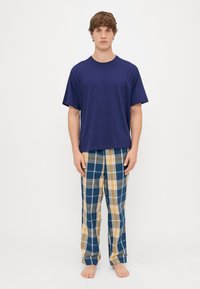 Tamsiai mėlynas medvilninis marškinėliai derinami su languotomis pižamomis mėlynos, geltonos ir pilkos spalvų. Patogus kirpimas su trumpomis rankovėmis ir elastinga juosta.