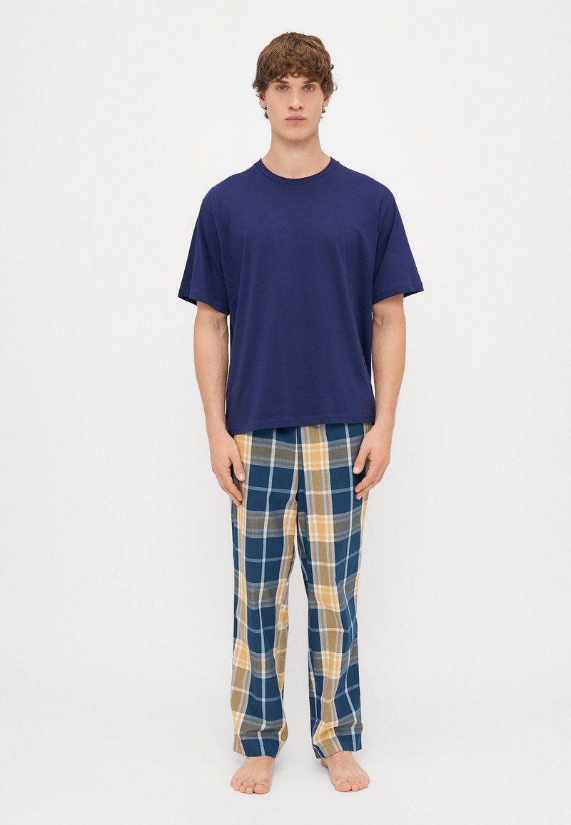 Tamsiai mėlynas medvilninis marškinėliai derinami su languotomis pižamomis mėlynos, geltonos ir pilkos spalvų. Patogus kirpimas su trumpomis rankovėmis ir elastinga juosta.