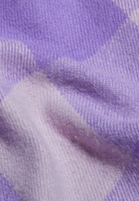 Tessuto a scacchi viola realizzato in morbida lana testurizzata, con blocchi più chiari e più scuri, creando un accogliente motivo a quadretti.
