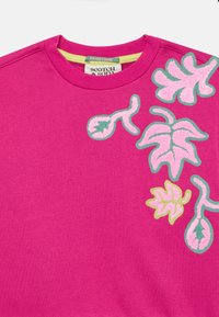 Fuksia sweatshirt med rund hals, med broderte blader og blomsterdesign i rosa og grønt på den ene siden.