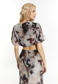 Completo in due pezzi con top corto a maniche puff e gonna lunga, realizzato in tessuto leggero con un motivo astratto multicolore.