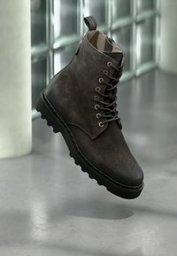 Stivaletto alla caviglia con lacci in pelle grigio scuro, superficie testurizzata, punta tonda, suola robusta, occhielli metallici, linguetta posteriore per facilitare la calzata.