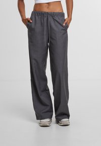 Grijze, wijde broek van stof met een gladde textuur. Voorzien van een elastische tailleband met een trekkoord en twee zijzakken.