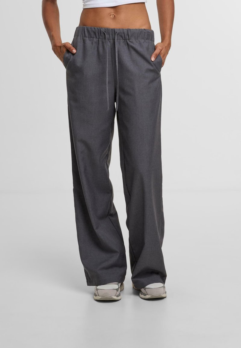 Grijze, wijde broek van stof met een gladde textuur. Voorzien van een elastische tailleband met een trekkoord en twee zijzakken.