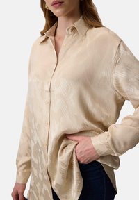 Beige overhemd met knopen gemaakt van een soepele stof, met een subtiele patroonstructuur en klassieke kraag. Slim fit met lange mouwen.