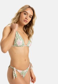 Groene en roze bloemenbikini met een driehoekstop met verstelbare banden, een patroontextuur en minimale bedekking aan de onderkant.