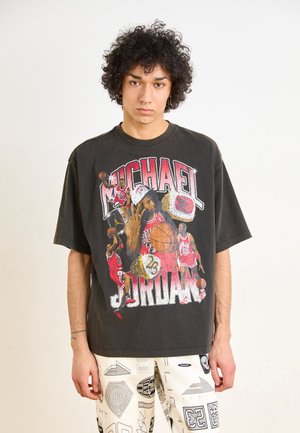 Svart oversized t-shirt med en grafik av Michael Jordan tillsammans med basketbollar och ringar. Tyget verkar mjukt med en vintage, väldistressad look.
