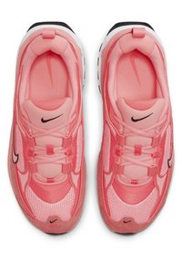 Vaaleanpunaiset urheilujen kengät, jotka on valmistettu verkosta ja nurmesta, näyttävät kerrokselta. Niissä on nauhakiinnitys ja musta Nike-logo sivussa.