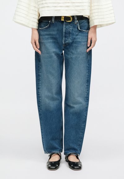 Svetlomodré rifle z denimu so strihom na rovno, stredne vysokým pásom, päťvreckovým dizajnom a jemným vyblednutím. Kombinované s čiernym opaskom a topánkami.