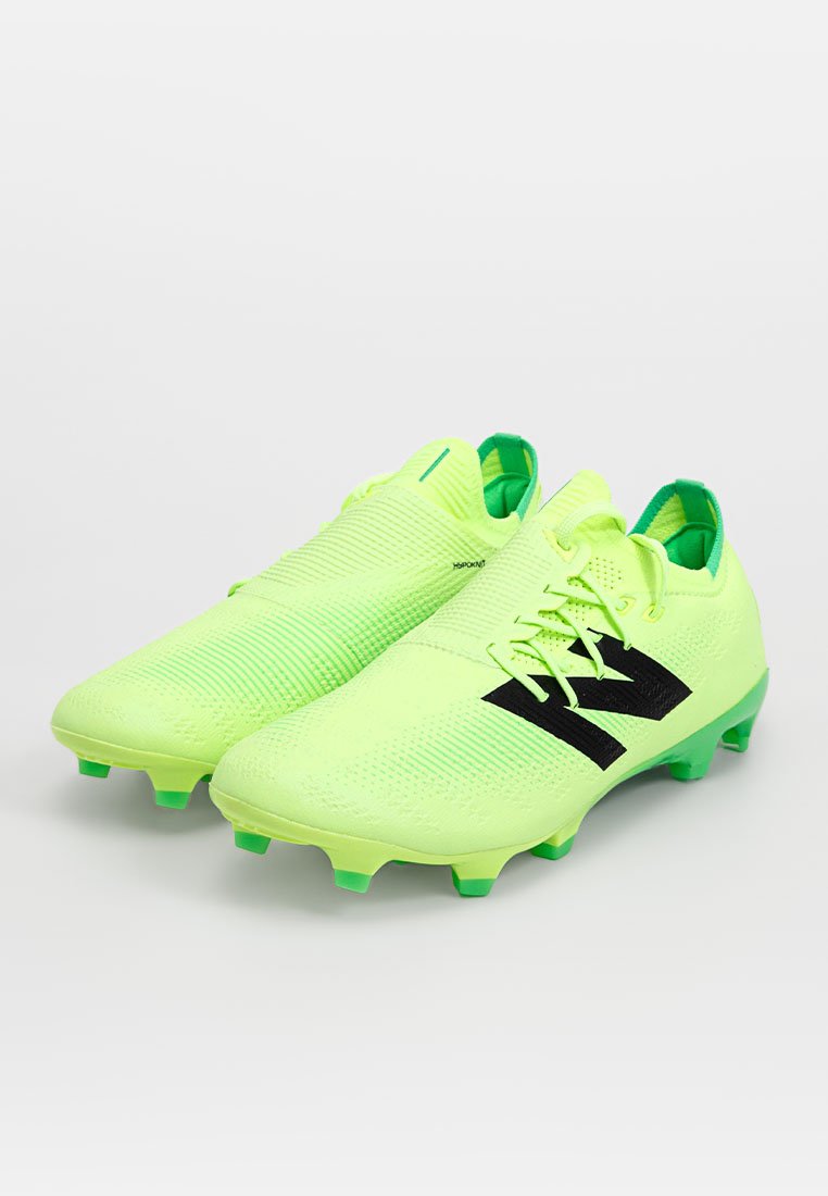Heldere neongroene voetbalschoenen met een gestructureerde bovenkant en zwarte accenten, met een laag profiel en gevormde noppen voor grip.