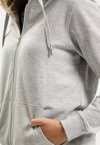 Jasnoszara bluza z kapturem na zamek, wykonana z miękkiego materiału, posiada podszewkę w kapturze, przednie kieszenie oraz ściągacze przy nadgarstkach. Gładka tekstura i minimalistyczny design.