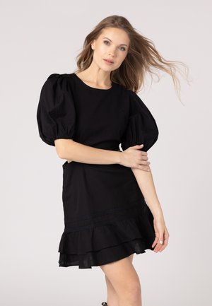 Black dress with short puff sleeves, a fitted bodice, and a layered ruffle hem. Made of textured fabric, featuring a lace trim detail.
