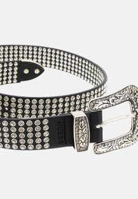 Juodas odinis diržas, puošiamas sidabriniais rhinestones, su puošniu metaliniu sagtimi, turinčia dekoratyvinius akcentus ir tekstūruotą paviršių.