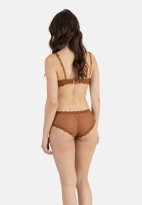 Ensemble de lingerie en dentelle marron présentant un motif texturé à pois, des bretelles réglables et des bords en dentelle festonnés sur le soutien-gorge et la culotte.