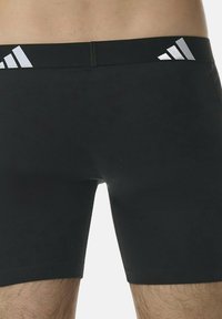 Pantaloni sportivi neri realizzati in materiale elasticizzato con una vestibilità aderente, caratterizzati da un design del logo argento sull'orlo elastico.