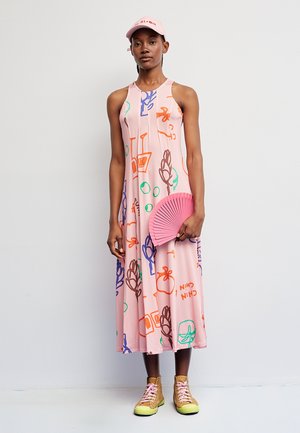 Vestido rosa sin mangas con patrones abstractos coloridos; combinado con una gorra rosa a juego, un abanico rosa como accesorio y zapatillas deportivas amarillo-verde.