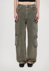 Cargo-Hosen aus olivgrünem Denim mit großen Seitentaschen, weitem Schnitt und sichtbaren Nähdetails. Strukturierter Bund mit Knopfverschluss.