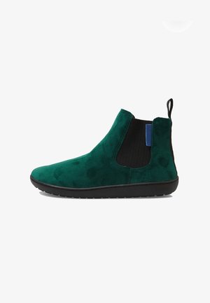 Bottine en suede verte avec un panneau latéral élastique noir, une languette à l'arrière et une semelle en caoutchouc noire, présentée en profil latéral.