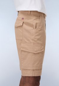 Brune cargo shorts lavet af letvægtsstof, med sidelommer, syede detaljer og et lille flagmærke på forsiden.