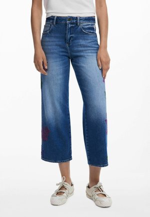 Wijduitlopende denim jeans in een middelblauwe wassing, met bloemige borduursels in rood en groen op beide benen. Klassieke vijf-pocketstijl.