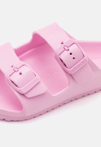 Sandal de borracha rosa com duas alças ajustáveis e fivelas a condizer. A palmilha e a sola texturizadas oferecem aderência e conforto.