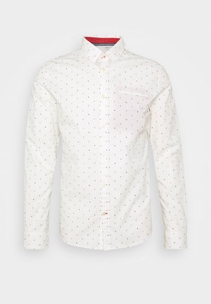 Weißes langärmeliges Hemd mit Knopfleiste, einem kleinen, mehrfarbigen Punktemuster und einem inneren roten Kragendetail, auf neutralem Hintergrund präsentiert.