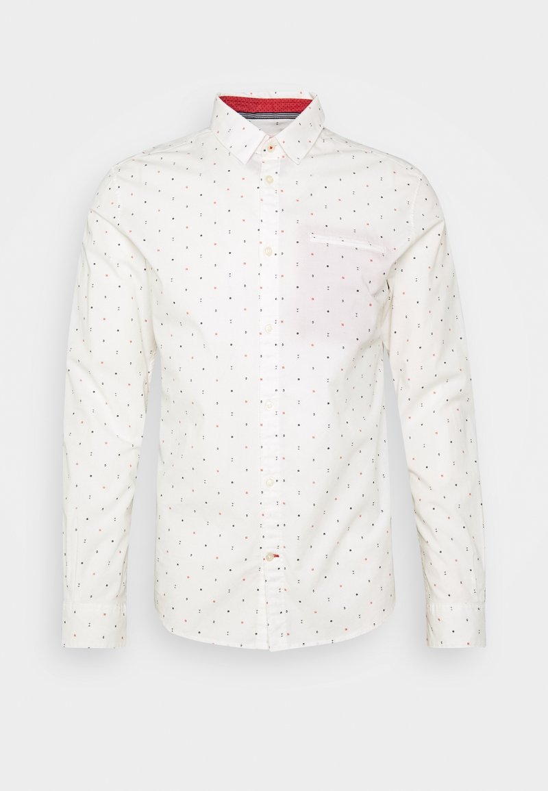 Chemise blanche à manches longues avec boutons, présentant un petit motif de points multicolores et un détail de col intérieur rouge, affichée sur un fond uni.