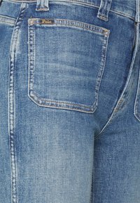 Světle modré džíny z denimu s malou zadní kapsou a zlatou etiketou "Polo", klasický pětikapsový design a jemné vzory blednutí.