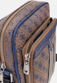 Braune und blaue gemusterte Tragetasche aus Canvas mit zwei Reißverschlussfächern, strukturiertem Finish und silbernen Hardware-Details. Verfügt über einen Lederbesatz.
