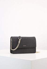 Borsa a tracolla nera DKNY con superficie texture, tracolla in catena dorata, chiusura magnetica e dettaglio logo sul davanti.