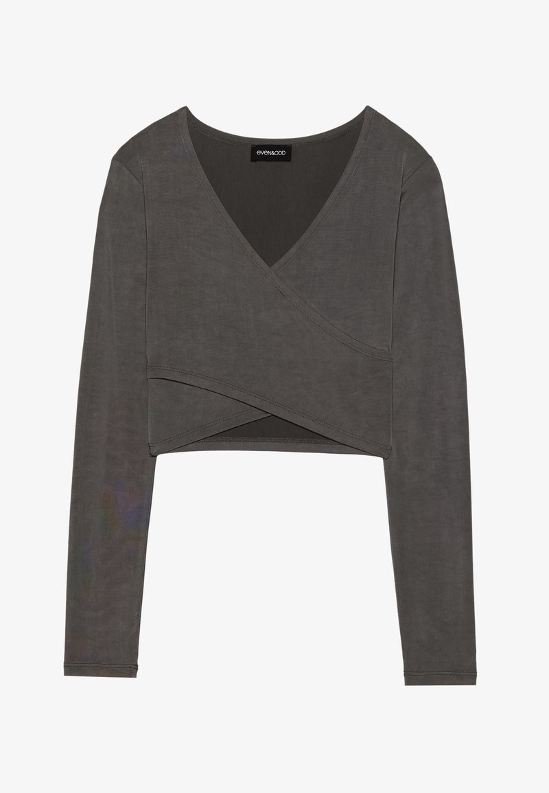 Haut court gris à manches longues avec un design croisé et un col en V, featuring un tissu lisse et des détails de couture subtils. Étiquette de marque visible à l'intérieur.