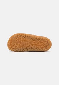 Gummi yttersåle med en gumfarge, med et teksturert grepemønster som inkluderer sikksakk- og firkantmotiver, samt et logoavtrykk.