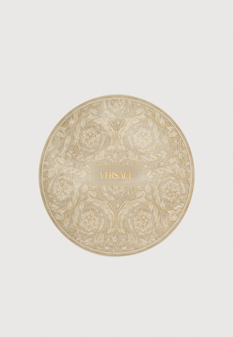 Στρογγυλό διακοσμητικό συμπαγές σ ε μπεζ και χρυσό, με λουλουδάτα μπαρόκ μοτίβα και το λογότυπο "VERSACE" ανάγλυφο στο κέντρο.