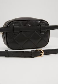 Borsa a tracolla nera in pelle trapuntata con forma rettangolare, caratterizzata da una fibbia in tono oro e una tracolla regolabile. Texture liscia e design essenziale.