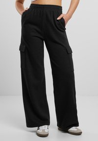 Schwarze weite Cargo-Hosen aus weichem Stoff, mit einem elastischen Bund und Seitentaschen für Funktionalität.