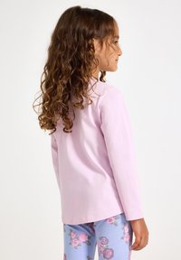 Μακρυμάνικη κορυφή σε λιλά χρώμα με στρογγυλή λαιμόκοψη, συνδυασμένη με ανοιχτό μπλε κολάν που διαθέτει μοτίβο ροζ τριαντάφυλλου. Μαλακό βαμβακερό υλικό.