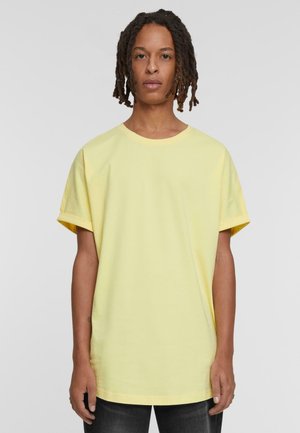 Gul oversized t-skjorte laget av myk bomull, med rund hals, korte ermer og løs passform. Ingen synlige mønstre eller hardware.