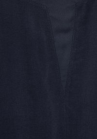 Tkanina w kolorze granatowym o gładkiej fakturze. Posiada dekolt w kształcie litery V, subtelne przeszycia oraz czysty, minimalistyczny design.