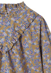 Blumenmuster auf einem senfgelben Stoff mit Rüschendetail am Ausschnitt; zeigt blau und rosa florale Motive auf einer weichen Textur.