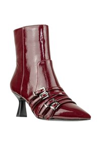 Stivale alla caviglia in pelle verniciata bordeaux con punta appuntita, caratterizzato da tre cinturini orizzontali e fibbie argento. Design con tacco a stiletto.
