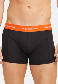 Schwarze Boxerbriefs aus glattem Stoff. Mit einem orangen elastischen Bund, der den Text "Originals Studio" trägt. Enger Sitz mit Stichakzenten.