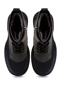 Zwarte leren enkelboots met gestructureerde rubberen zolen, ronde neuzen en opvallende veters. Voering van zacht grijs bont. Accenten van zilveren hardware.