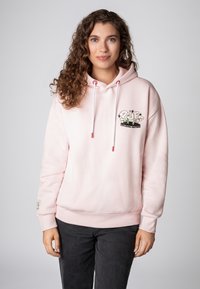 Lichtroze hoodie met een voorzak, een trekkoord capuchon en geborduurde afbeelding met de tekst "EXPLODING EMOTIONS." Zachte textuur, casual pasvorm.