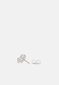 Silver metal stud earrings with a twisted knot design. Accompanied by a butterfly clutch back for secure fastening. Smooth texture.