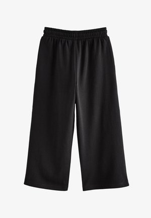 Zwarte wijde broek met elastische tailleband, gemaakt van zachte stof, plat neergelegd op een witte achtergrond.