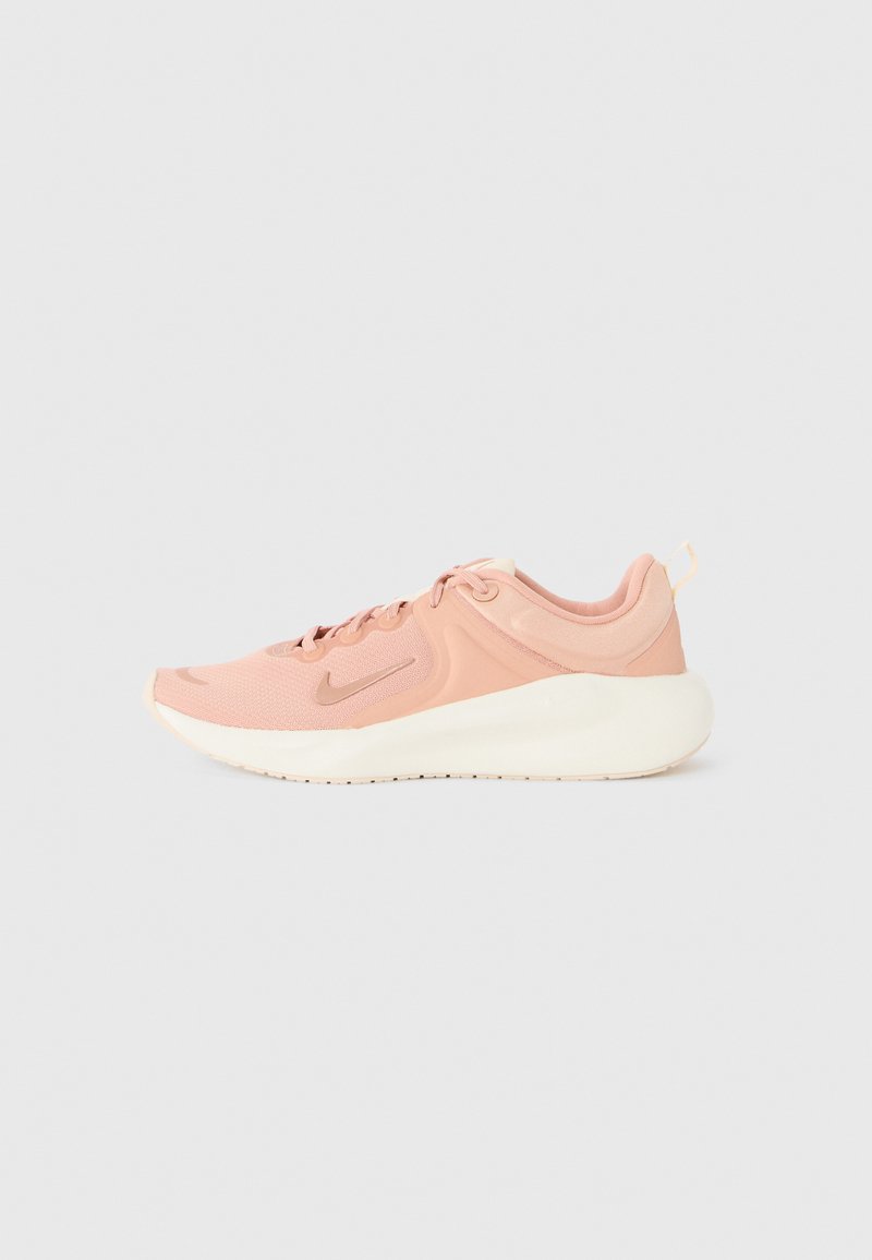 Ténis Nike com um upper de malha rosa, entressola creme e sola de borracha texturizada; apresenta atacadores e uma aba no calcanhar para facilitar o uso.