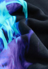 Bunt bedruckter Stoff mit blauen und lila abstrakten Mustern auf schwarzem Hintergrund, der eine glatte Textur und unterschiedliche Farbtöne aufweist.