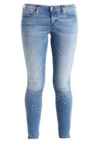 Tight jeans i ljusblå denim med slitningar och små hål, med slim fit och dragkedjedetaljer vid anklarna.