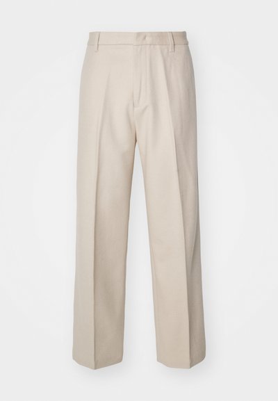 Calças beje ajustadas com um corte reto, apresentando uma textura suave, linha de pregas central e cintura standard com passantes para cinto.